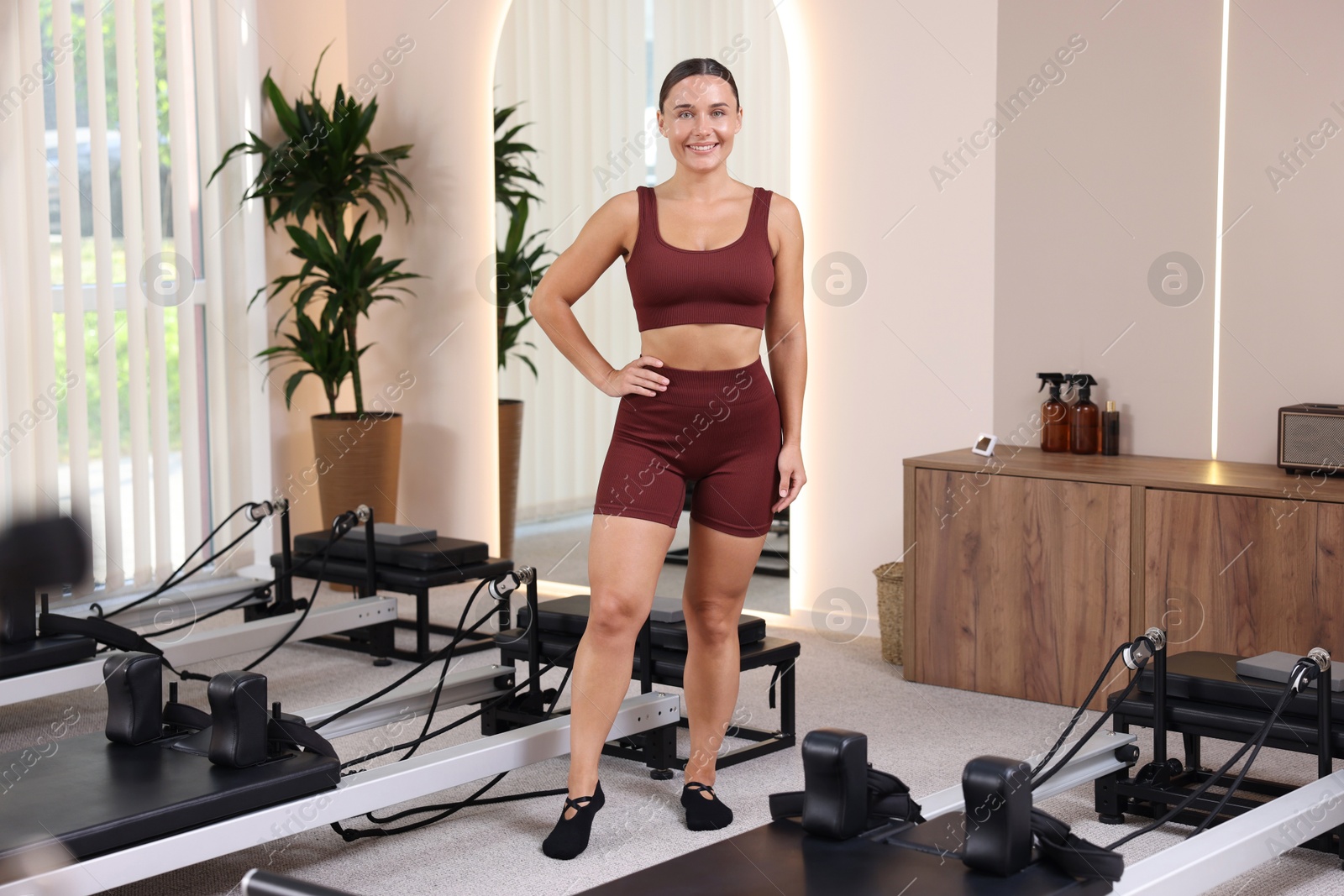 Happy woman near reformer in pilates studio Photo of Happy woman near reformer in pilates studio