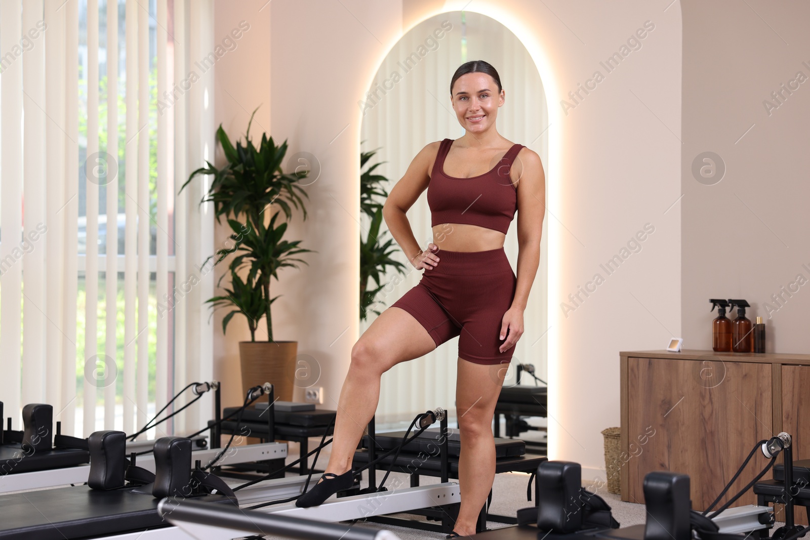 Happy woman near reformer in pilates studio Photo of Happy woman near reformer in pilates studio