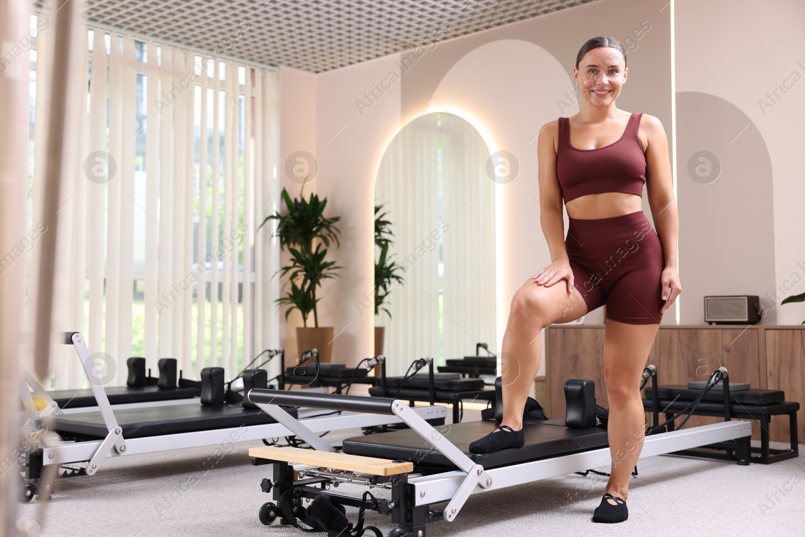 Happy woman near reformer in pilates studio Photo of Happy woman near reformer in pilates studio