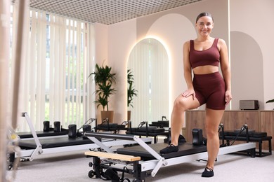 Photo of Happy woman near reformer in pilates studio