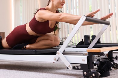 Photo of Woman exercising on reformer in pilates studio, closeup