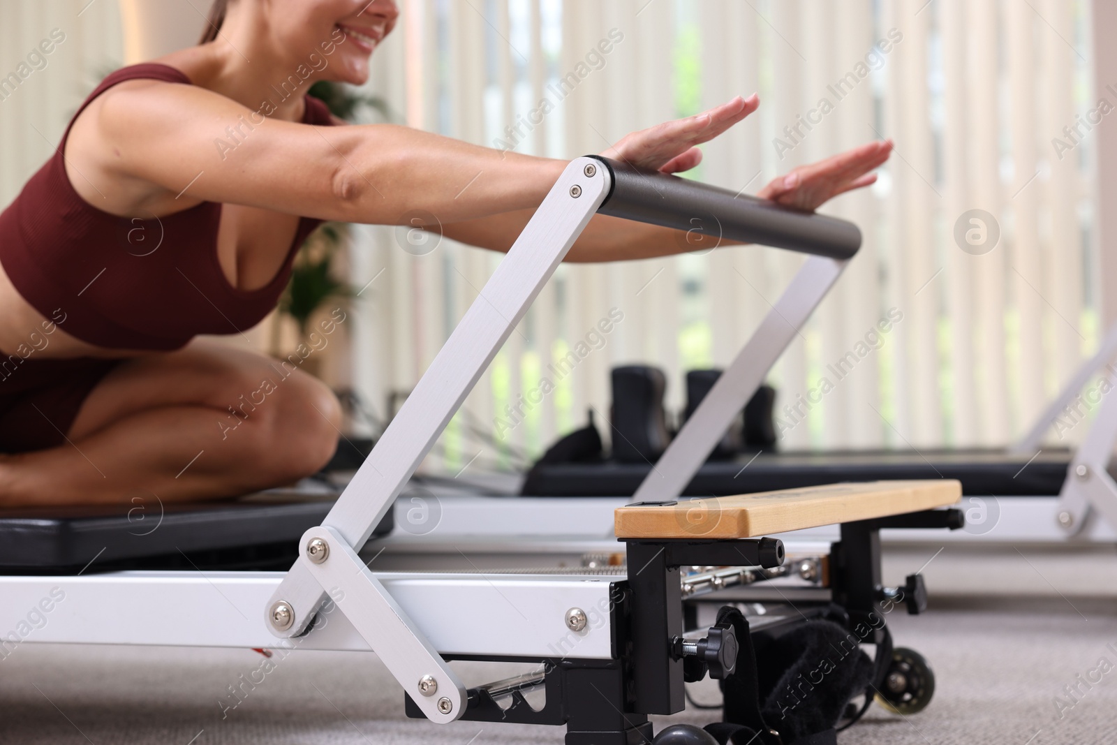 Photo of Woman exercising on reformer in pilates studio, closeup