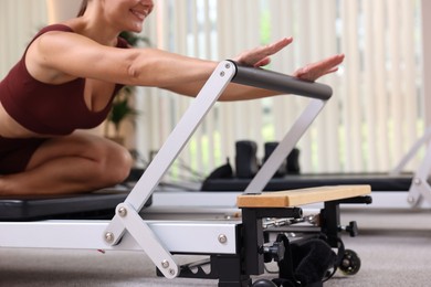 Photo of Woman exercising on reformer in pilates studio, closeup