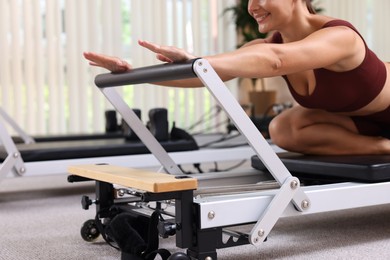 Photo of Woman exercising on reformer in pilates studio, closeup