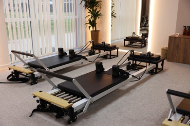 Photo of Reformer machines and mirror in studio. Pilates equipment
