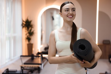 Photo of Woman with fitness mat in pilates studio, space for text