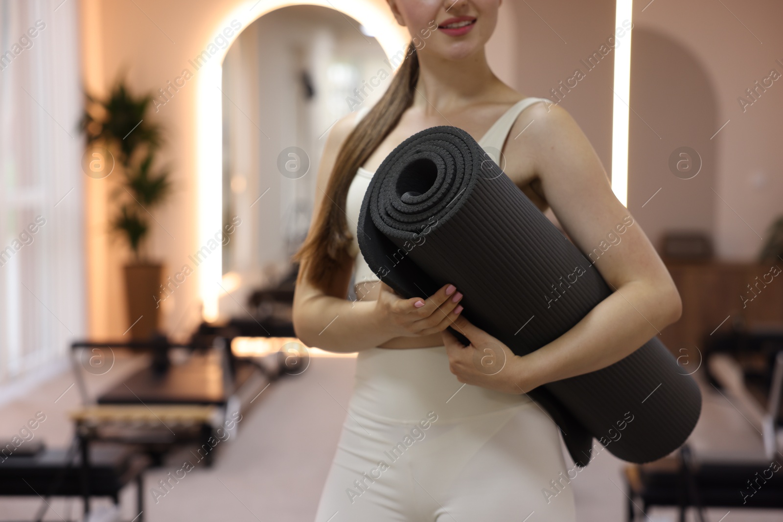 Woman with fitness mat in pilates studio, closeup. Space for text Photo of Woman with fitness mat in pilates studio, closeup. Space for text