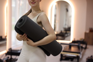 Photo of Woman with fitness mat in pilates studio, closeup. Space for text