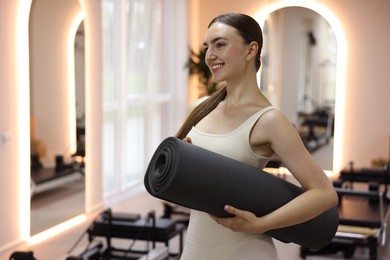 Photo of Woman with fitness mat in pilates studio, space for text