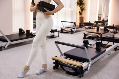 Photo of Woman with foam blocks near reformer in pilates studio, closeup
