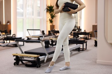 Photo of Woman with foam blocks near reformer in pilates studio, closeup