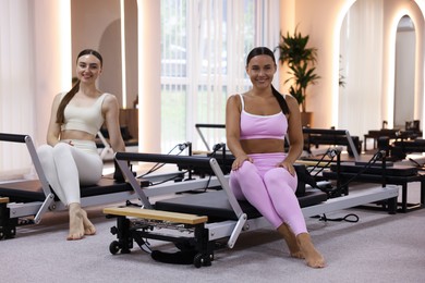 Photo of Woman and pilates instructor on reformers in studio