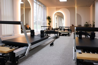Photo of Many reformers in studio, closeup. Pilates equipment