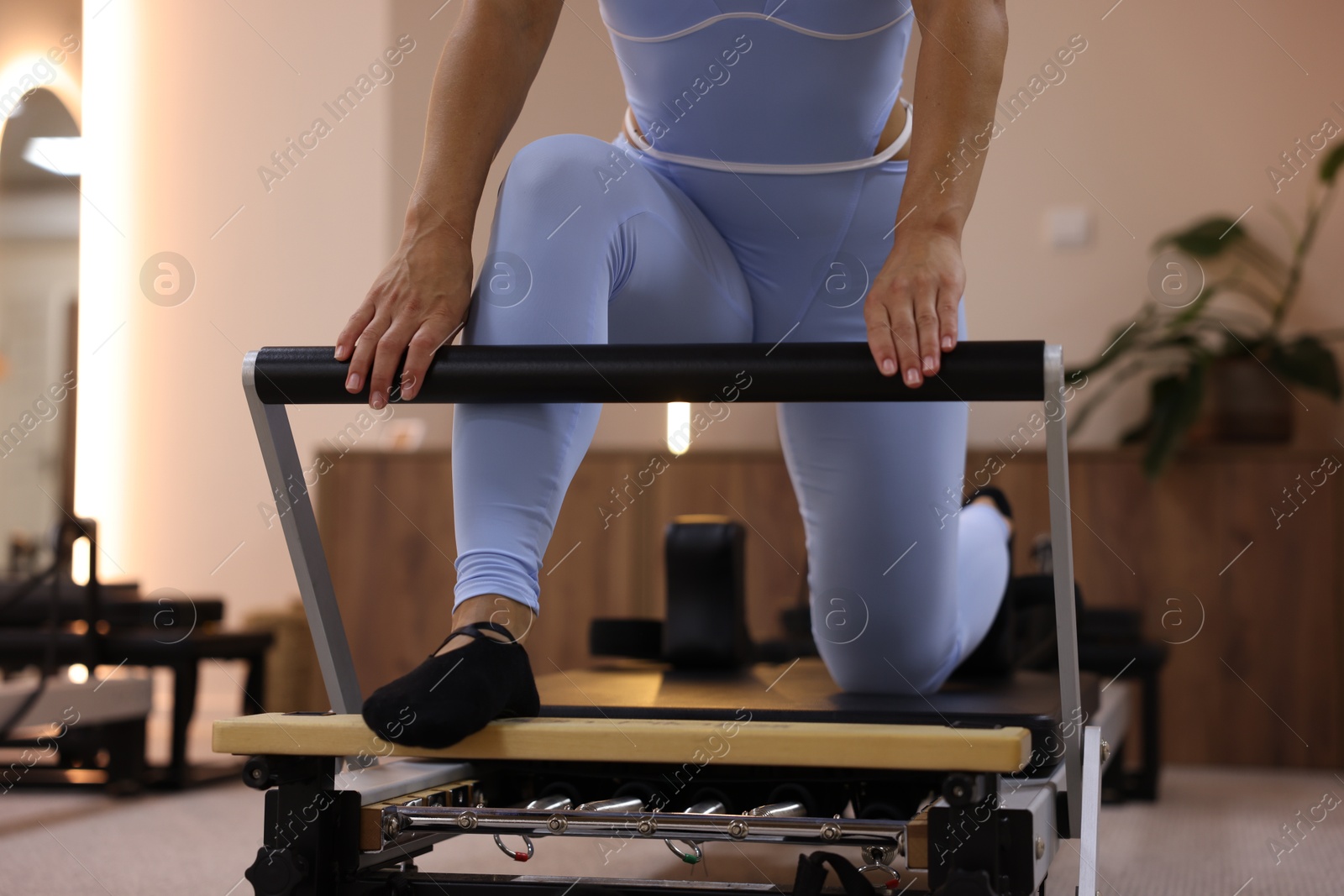 Woman exercising on reformer in pilates studio, closeup Photo of Woman exercising on reformer in pilates studio, closeup