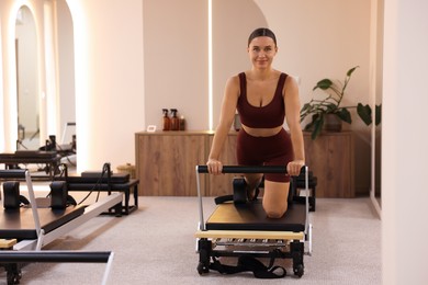 Photo of Woman exercising on reformer in pilates studio