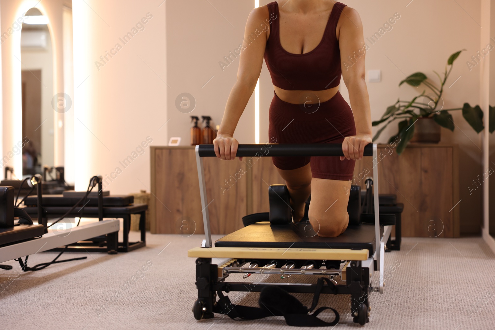Photo of Woman exercising on reformer in pilates studio, closeup