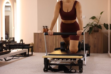 Photo of Woman exercising on reformer in pilates studio, closeup