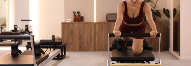 Photo of Woman exercising on reformer in pilates studio, closeup. Space for text