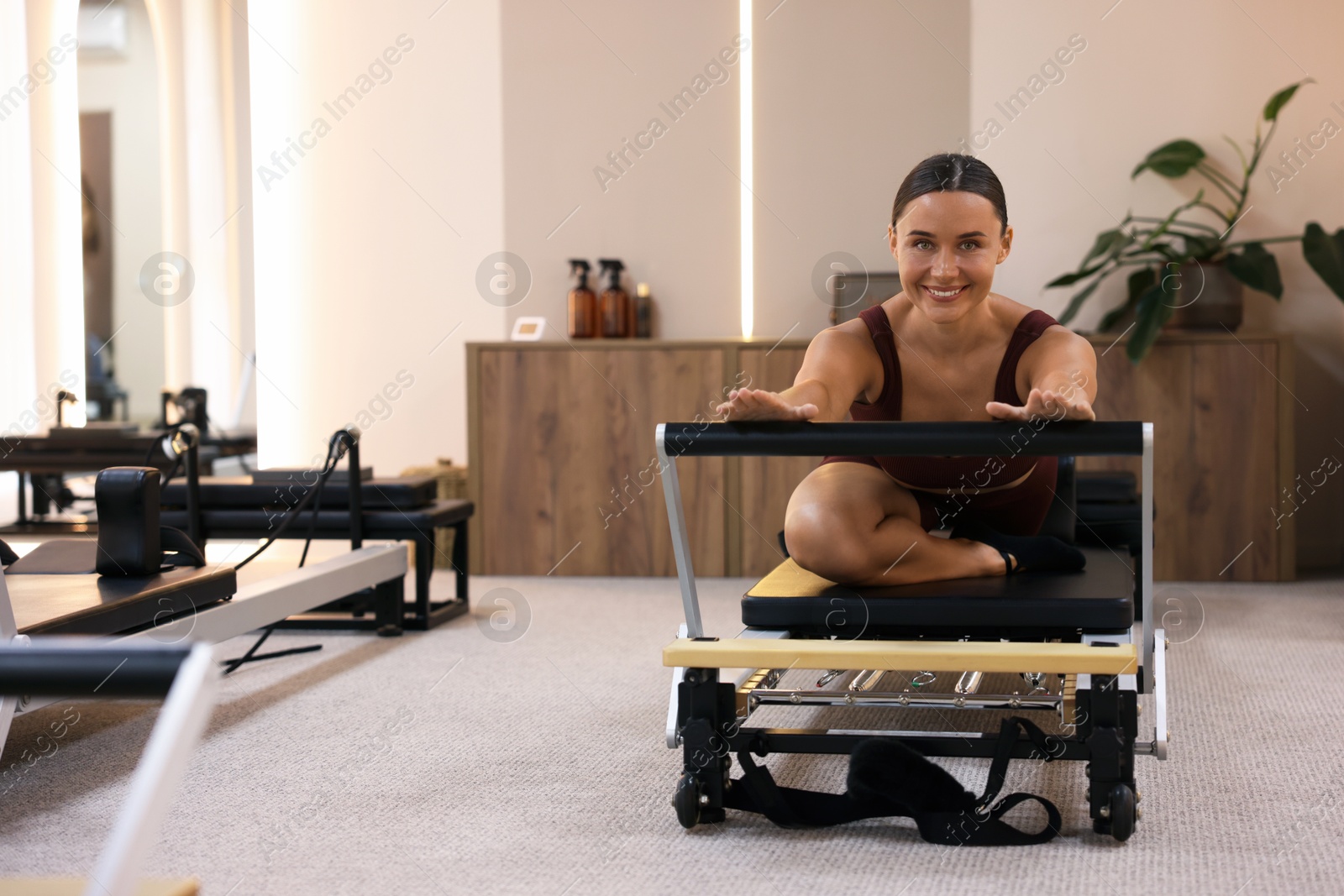 Photo of Woman exercising on reformer in pilates studio, space for text