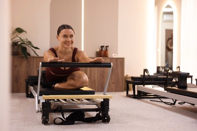 Photo of Woman exercising on reformer in pilates studio, space for text