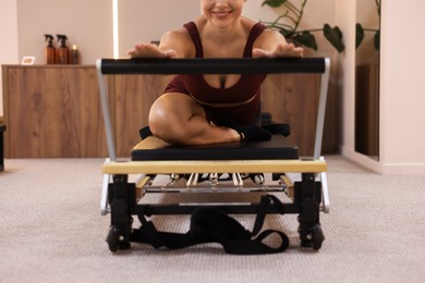 Photo of Woman exercising on reformer in pilates studio, closeup