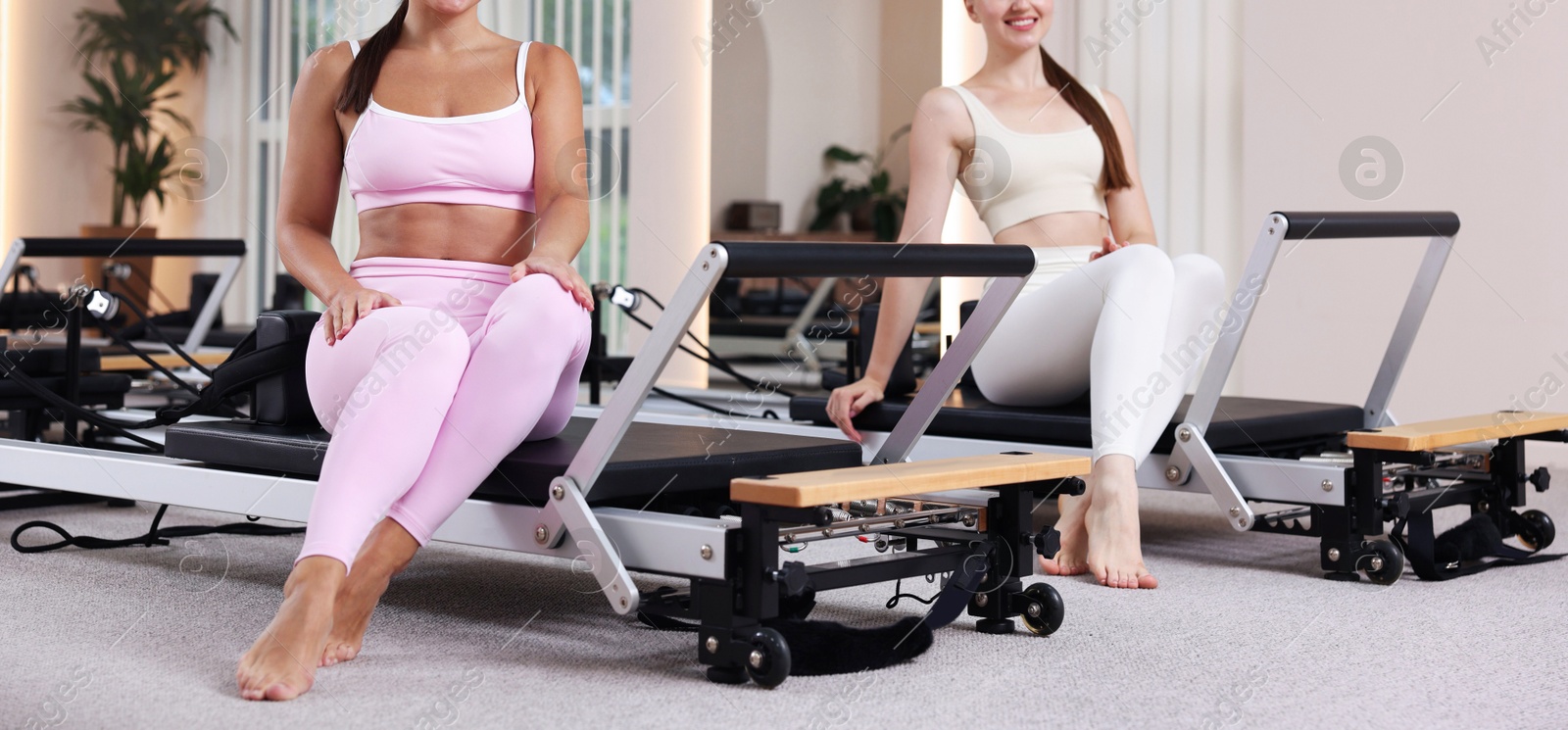 Photo of Woman and pilates instructor on reformers in studio, closeup
