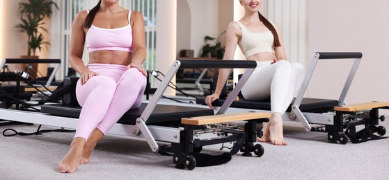 Photo of Woman and pilates instructor on reformers in studio, closeup