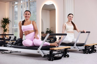 Photo of Woman and pilates instructor on reformers in studio