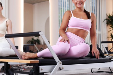 Photo of Woman and pilates instructor on reformers in studio, closeup