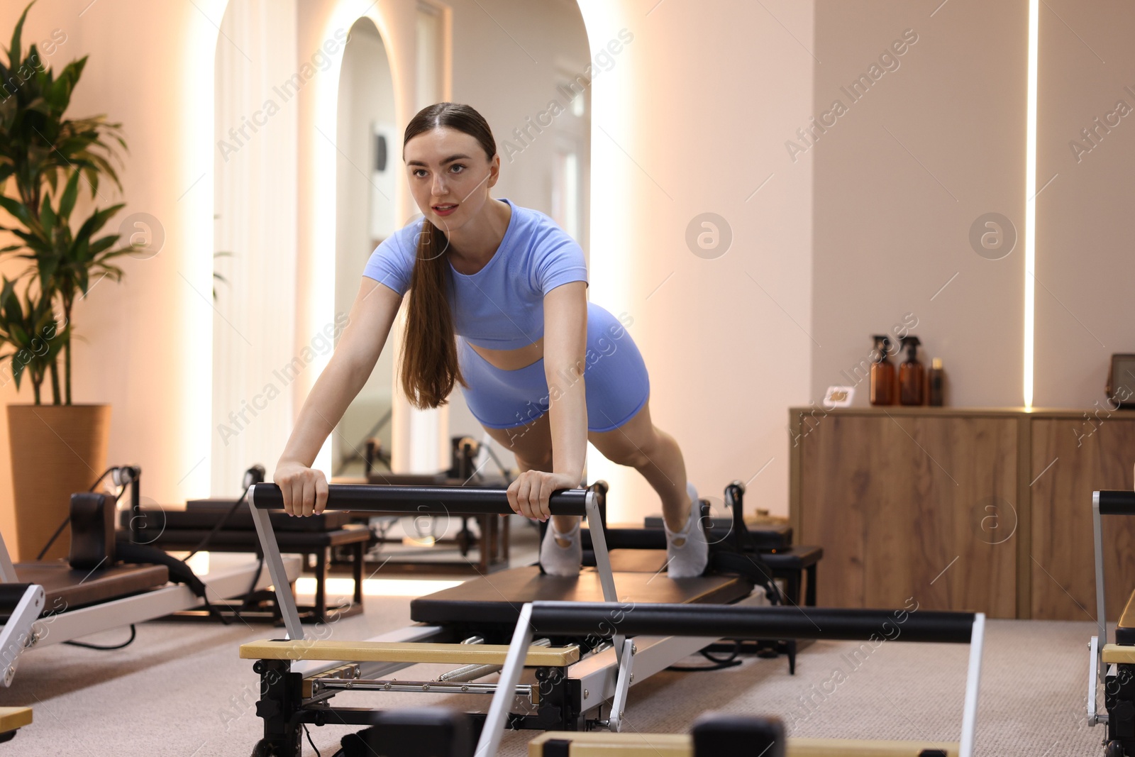 Photo of Woman exercising on reformer in pilates studio