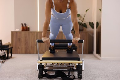 Photo of Woman exercising on reformer in pilates studio, closeup