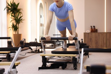 Photo of Woman exercising on reformer in pilates studio, closeup