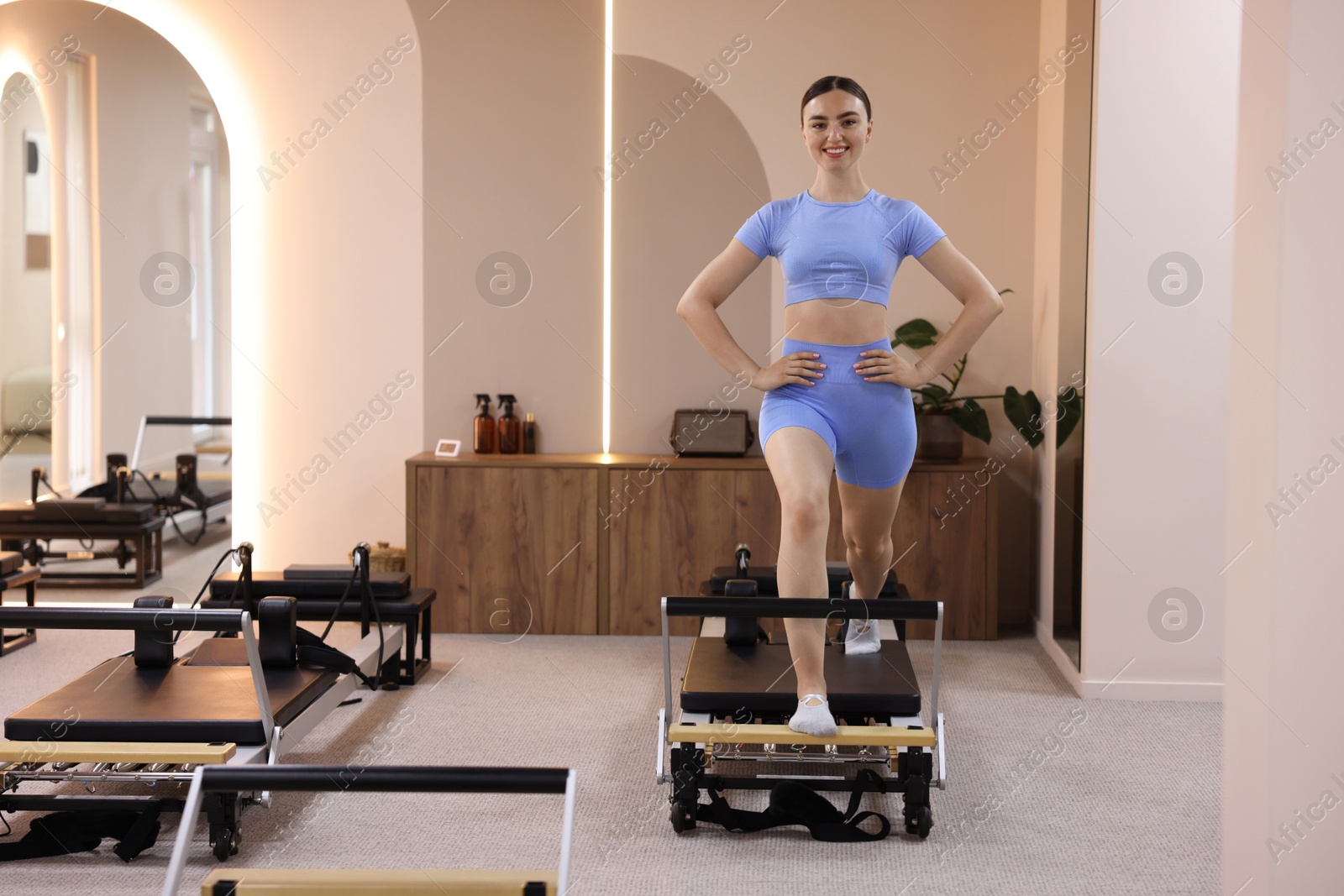 Woman exercising on reformer in pilates studio, space for text Photo of Woman exercising on reformer in pilates studio, space for text