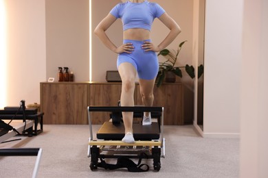 Photo of Woman exercising on reformer in pilates studio, closeup