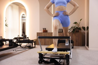 Photo of Woman exercising on reformer in pilates studio, closeup