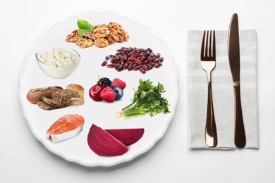 Image of Plate with collection of different foods and cutlery on white background, top view. Healthy eating