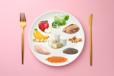 Image of Plate with collection of different foods and cutlery on pink background, top view. Healthy eating