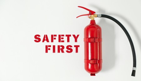 Image of Safety first, poster. Fire extinguisher hanging on white wall, banner design