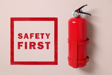 Image of Safety first, poster. Fire extinguisher hanging on pink wall