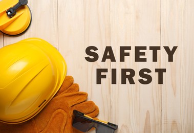 Image of Safety first, poster. Personal protective equipment on wooden background, top view