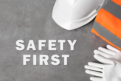 Image of Safety first, poster. Personal protective equipment on grey stone background, top view