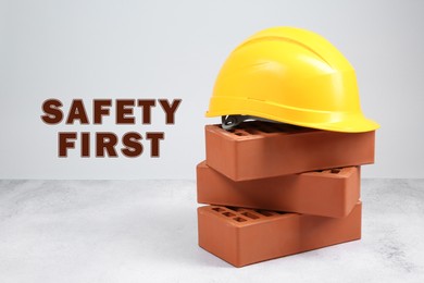 Image of Safety first, poster. Hard hat and bricks against white background