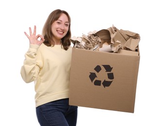 Photo of Recycling. Smiling woman holding cardboard box with different waste paper and showing OK gesture on white background