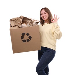 Photo of Recycling. Smiling woman holding cardboard box with different waste paper and showing OK gesture on white background