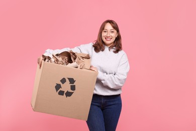 Photo of Recycling. Smiling woman holding cardboard box with different waste paper on pink background