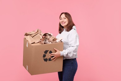 Photo of Recycling. Smiling woman holding cardboard box with different waste paper on pink background