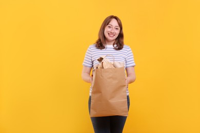 Photo of Recycling. Smiling woman with bag full of different waste paper on yellow background