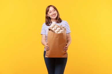 Photo of Recycling. Smiling woman with bag full of different waste paper on yellow background