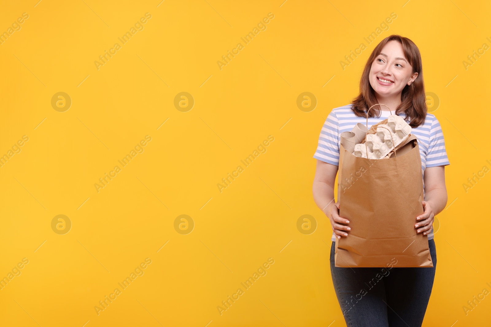 Photo of Recycling. Smiling woman with bag full of different waste paper on yellow background. Space for text