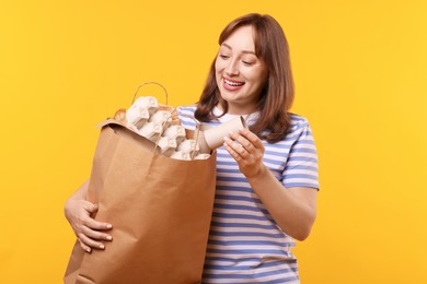 Photo of Recycling. Smiling woman with bag full of different waste paper on yellow background